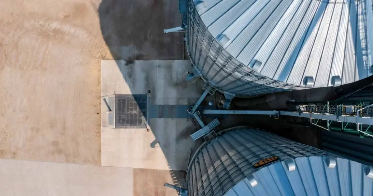 Aerial view of large steel grain storage bins and grain handling infrastructure