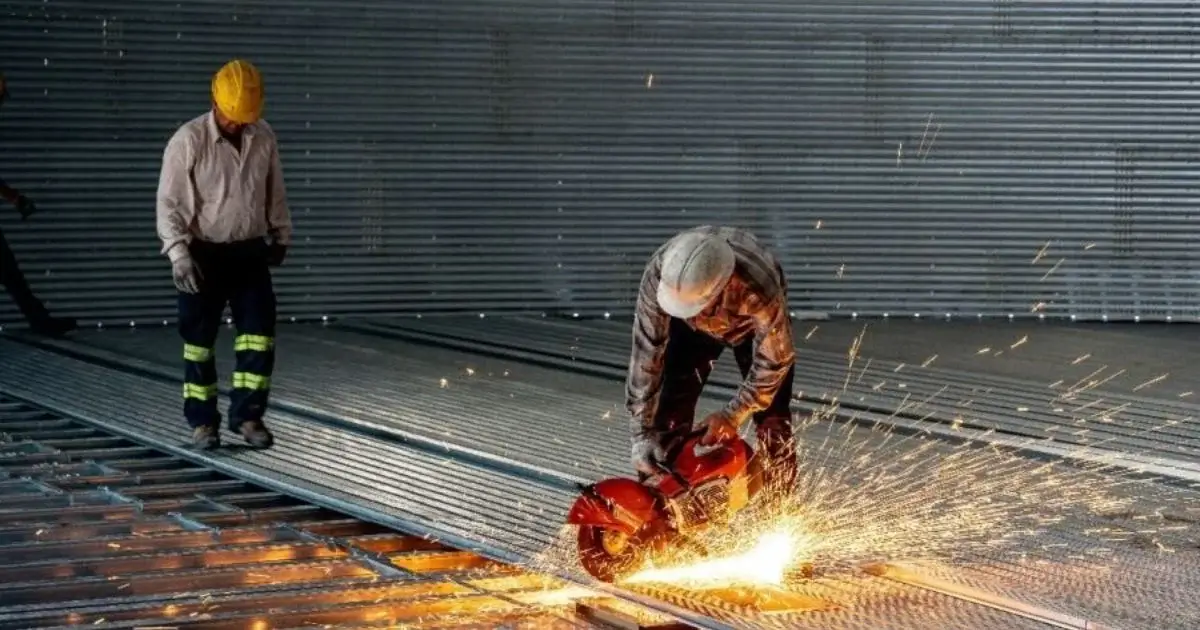 Workers cutting steel during grain bin construction and installation