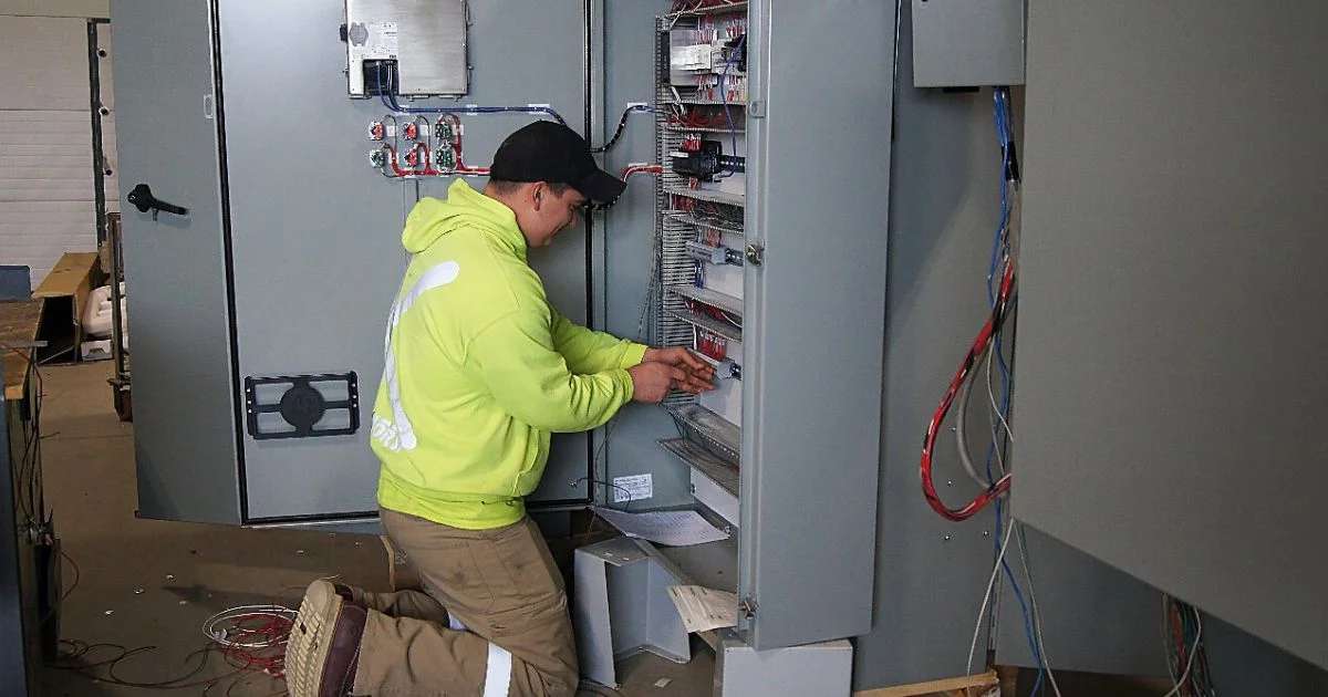Electrician working inside industrial electrical control panel