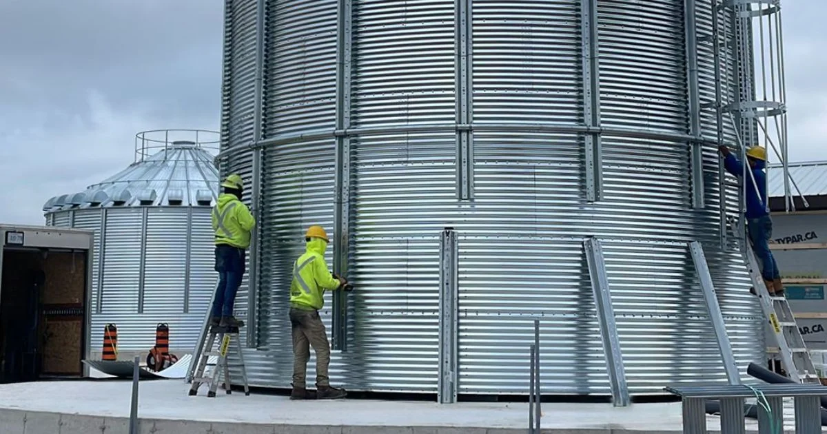 Workers installing large steel grain storage bin